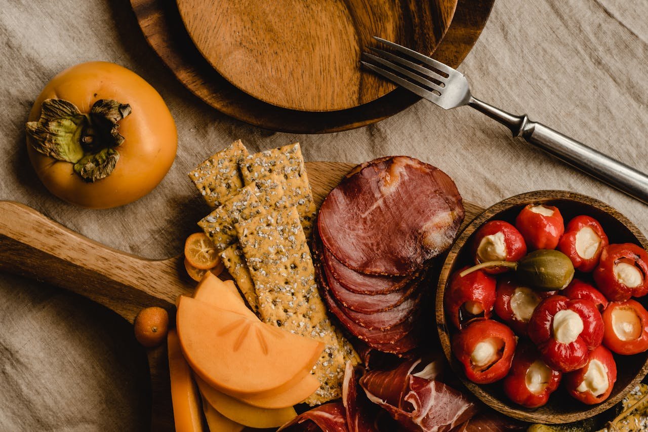 Explore a beautifully arranged charcuterie board featuring cured meats, stuffed peppers, crackers, and fruits.
